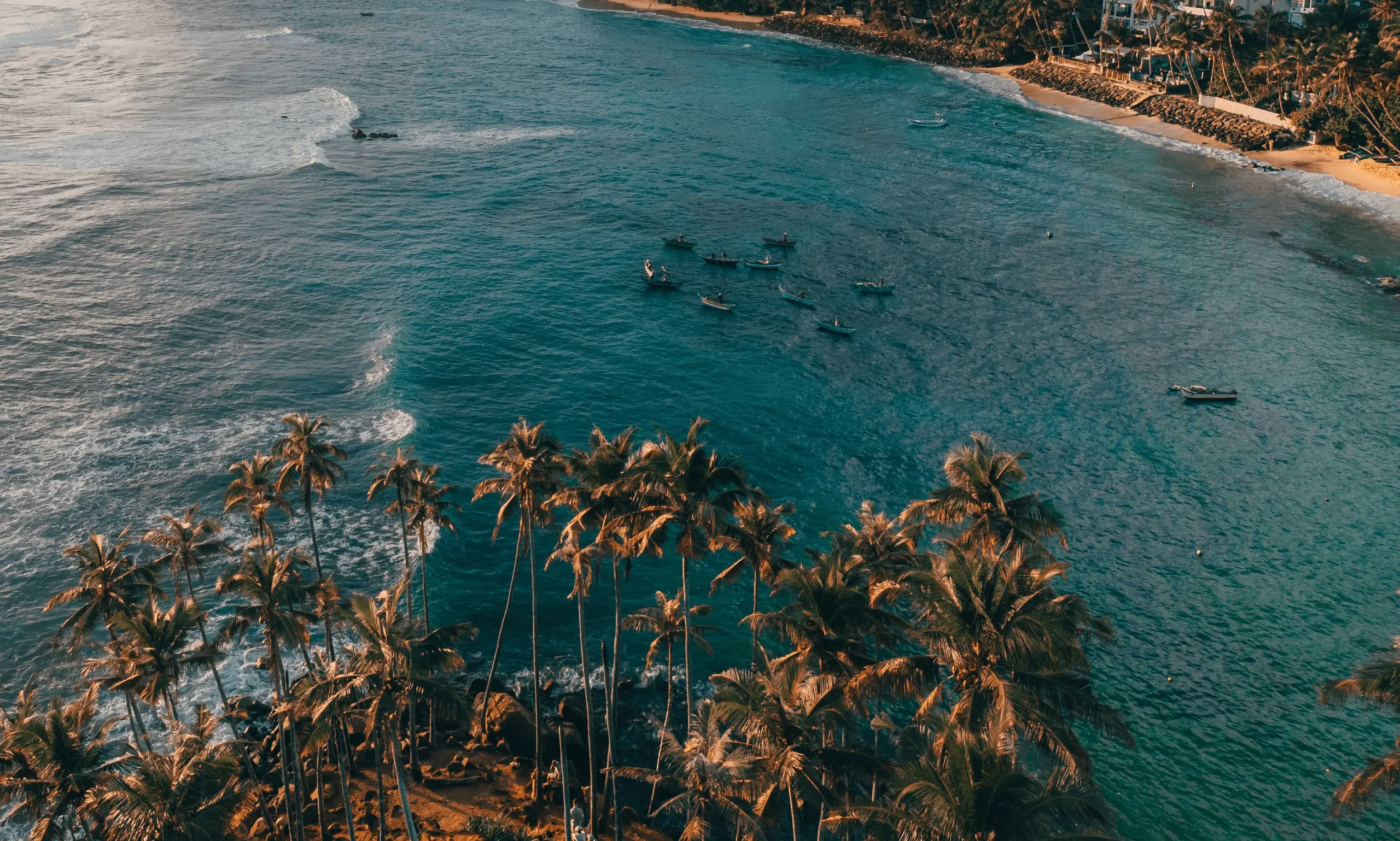 Aerial view of Mirissa's crescent bay with fishing boats anchored on turquoise water