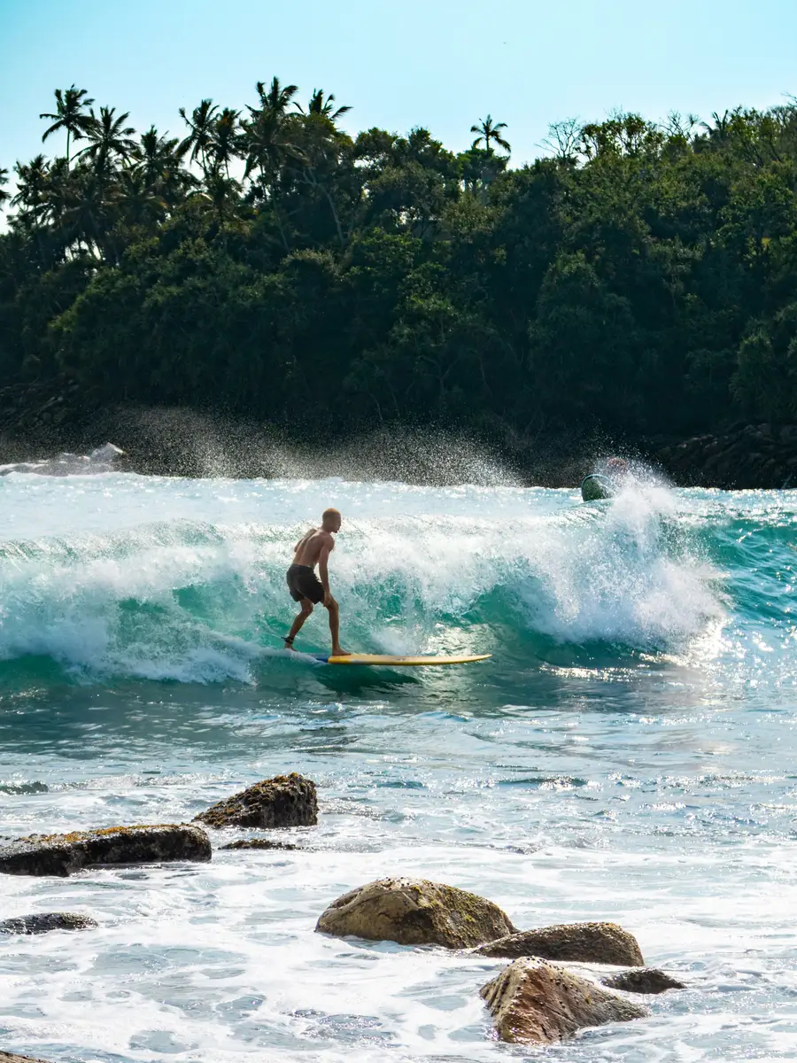 A longboarder gliding across a clean Mirissa wave